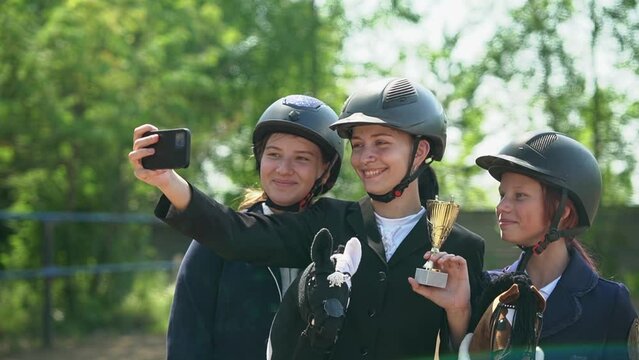 teenagers take a photo on a smartphone. Caucasian teenagers rejoice at the victory in the competition. Horseback riding. equestrian sport.Full HD video recording 