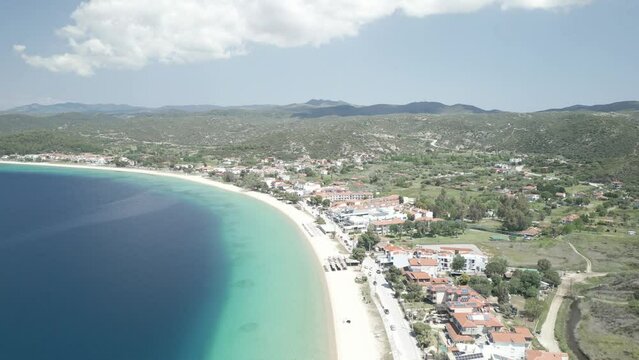 Aerial scene over Toroni Beach with houses coastline with cloudy sky in Greece