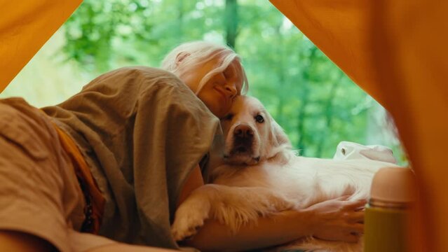 Caucasian woman petting her dog in a yellow camping tent