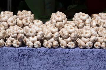 bunches of garlic are displayed on a presentation table for sale.
