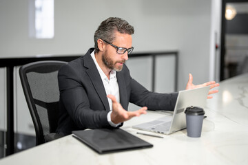 Naklejka premium Surprised businessman working with laptop in office. Surprised business man using laptop. Surprised man using laptop at office workplace. Surprised Ceo manager office worker business people.