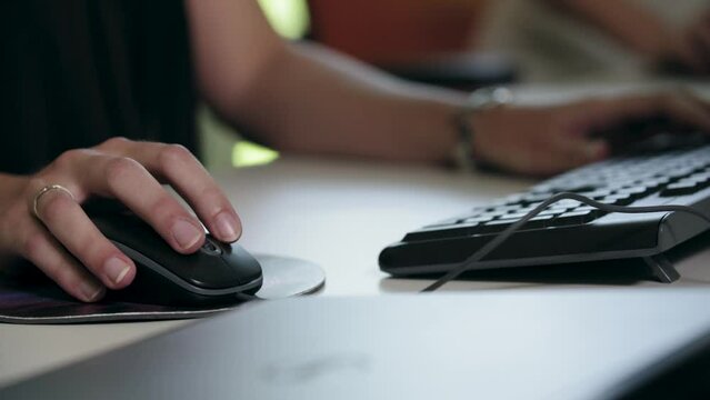 Closeup of a female using black mouse and keyboard of a computer
