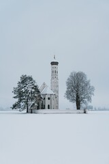 Stunning winter landscape featuring Coloman Church in Southern Germany blanketed in a layer of snow