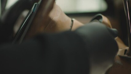 Close up view of male hand with black gloves, rotating or turning car key or gear shifting inside classic vintage suv car with beige colored interior : Concept of  robbery or thief . Jeep Wagoneer