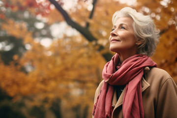 thoughtful senior woman in a jacket looking up in the autumn in the park. High quality photo