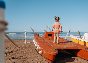  a little child girl playing on the beach at the sea and getting a lot of positive emotions from it