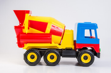 Multi-colored plastic toy trucks for children's games on a white background. Concrete mixer.