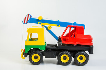 Multi-colored plastic toy trucks for children's games on a white background. Truck crane.