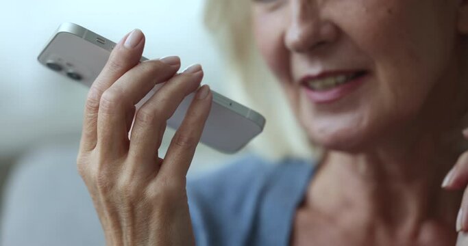 Positive old mature woman speaking on mobile phone call, talking on speaker, holding cellphone at mouth, using wireless Internet technology for communication. Lower face, smartphone close up