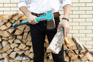 Closeup photo of businessman holding firewood and ax. Energy crisis concept