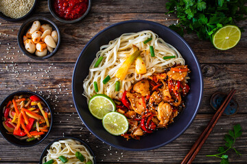 Asian food - chicken nuggets, noodles and stir fried vegetables on wooden table
