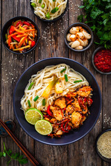Asian food - chicken nuggets, noodles and stir fried vegetables on wooden table
