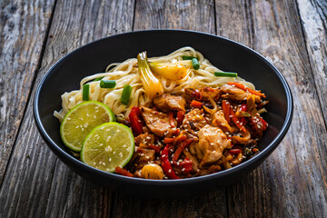 Asian food - chicken nuggets, noodles and stir fried vegetables on wooden table
