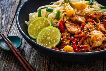 Asian food - chicken nuggets, noodles and stir fried vegetables on wooden table
