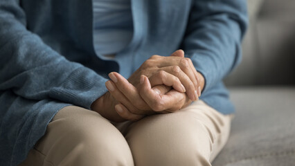 Mature old woman holding hands, folded palms on lap. Senior lady keeping arms gesture of waiting, anxiety, feeling lonely, concerned, going through health problems. Cropped close up banner shot