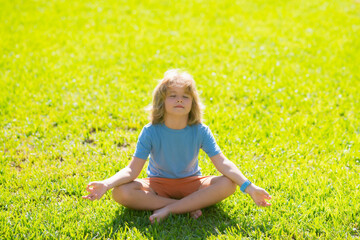 Child breathing fresh air. Child with close eye mindfulness meditating, sit on grass for peace and yoga. Kid relax on green grass.