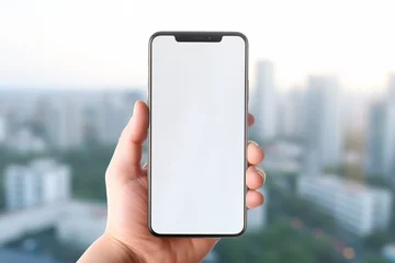 Deurstickers Mockup concept of a hand holding a modern smartphone with a white screen with a city landscape in the background. Generative AI © Dantaz