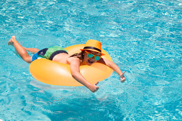 Summer fun. Kid boy splashing in swimming pool. Swim water sport activity on summer vacation with child. Child water toys, floating ring.