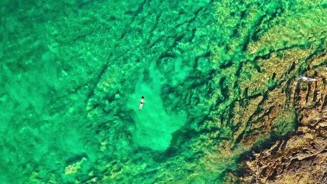 Luftaufnahme mit glücklicher und entspannter junger  Frau am Meeresstrand.