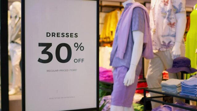 Dresses with sale 30 percent off. Close shot of advertising banner inside women's clothing store huge discount 30 percent on dresses. Shopping concept buy dress with sale 30 percent off and save money