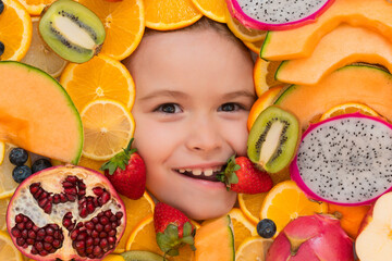 Healthy food background. Studio photo of different fruits with happy smiling kids face. Mix of different fruits and berries. Cute little boy eats fruits. Kid eating vitamins. Close up kids face.