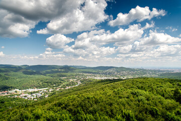 Fototapeta na wymiar Aerial view on the outskirts of Vienna city in Austria with the beautiful green hills of the Viennese forest and a dramatic sky in the summer 