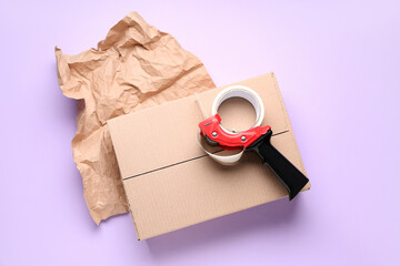 Packing tape dispenser, cardboard box and crumpled paper on lilac background