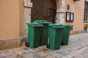 Rows of garbage cans of different colors in an alley in the city center, near a city cafe or...