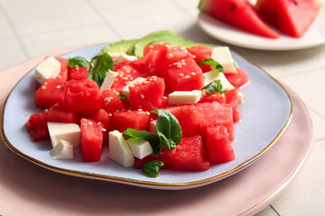 Plate of tasty watermelon salad on white tile background