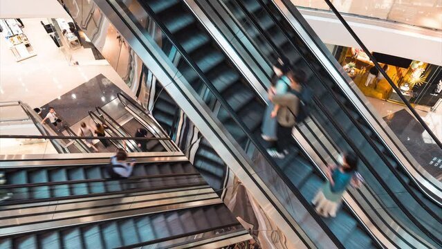 Timelapse of Asian people customer transport on escalator at urban shopping mall in Hong Kong. Department store business, financial economy, Asia city life, tourist traveler lifestyle. High angle view