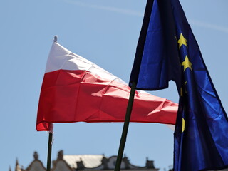 Flags of Poland and European Union waves on wind against blue sky
