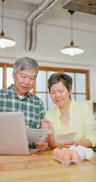 Asian elderly couple look bills