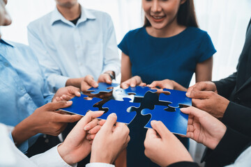 Diverse corporate officer workers collaborate in office, connecting puzzle pieces to represent...