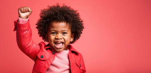 Black baby, kid with fist raised, black history month concept, african american girl, copyspace, blank space for text, inclusivity and diversity, protest, pink background
