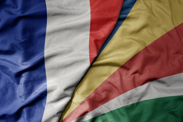 big waving realistic national colorful flag of france and national flag of seychelles .