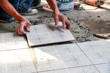 Floor tiles installation. Ceramic tiles and tools for tiler. Home improvement, hand of workers are...