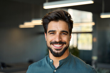Smiling handsome young business man looking at camera in office, headshot close up corporate...