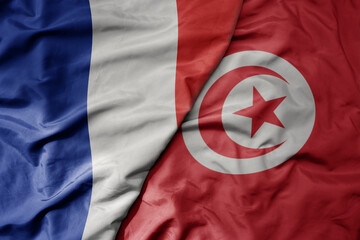 big waving realistic national colorful flag of france and national flag of tunisia .