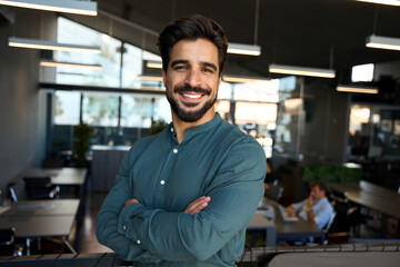 Happy young Latin professional business man looking at camera at work, portrait. Confident smiling...