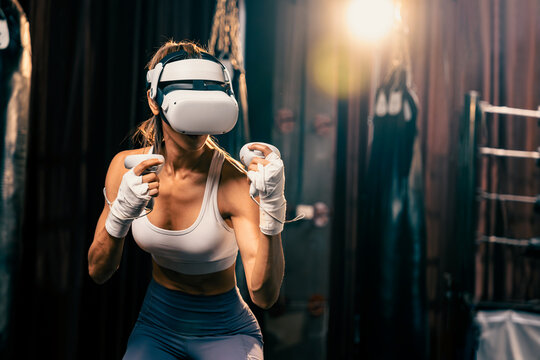 Female boxer training with VR or virtual reality, wearing VR headset with immersive boxing training technique using controller to enhance her skill in boxing simulator. Impetus