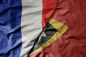 big waving realistic national colorful flag of france and national flag of east timor .