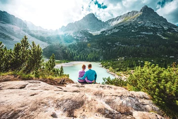 Fototapete Dolomiten Young sportive couple enjoys view on the turquoise Sorapis lake from a beautiful restpoint in the afternoon. Lake Sorapis, Dolomites, Belluno, Italy, Europe.