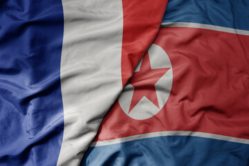 big waving realistic national colorful flag of france and national flag of north korea .