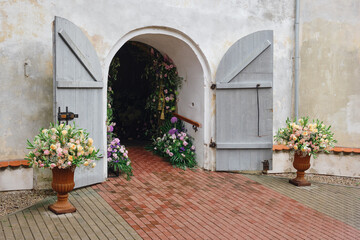 Fototapeta na wymiar The entrance to the building is beautifully and elegantly decorated with flowers for the holiday. Open doors to the church for the wedding ceremony.