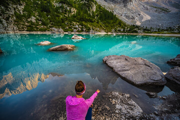 Young woman enjoys beautiful refelctions on turquoise Sorapis lake and dito di dio in the evening. Lake Sorapis, Dolomites, Belluno, Italy, Europe.