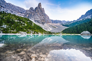 Naklejka na ściany i meble Beautiful reflections on turquoise Sorapis lake and with dito di dio in the background in the evening. Lake Sorapis, Dolomites, Belluno, Italy, Europe.