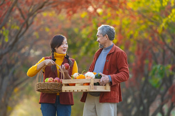 Happy farmer family carrying produce harvest with homegrown organics apple, squash and pumpkin with...