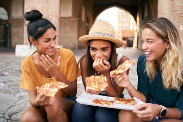  Three beautiful women sitting on the stairs of the city streets eating pizza from a street stall. The happy girls enjoy the weekend together. High quality photo © CarlosBarquero
