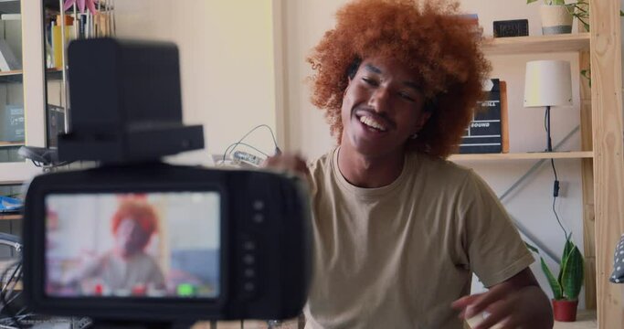 Young African American man recording video for social networks with a camera in an apartment. Digital content creator, streaming