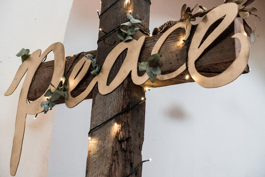 wooden rustic cross with the word peace in gold letters on it